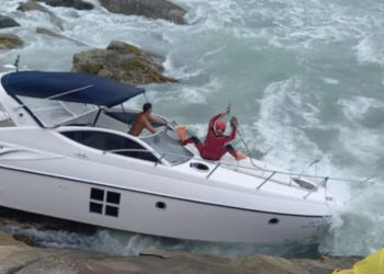 Lancha é rebocada após ser jogada contra costão na praia do Estaleirinho em Balneário Camboriú.