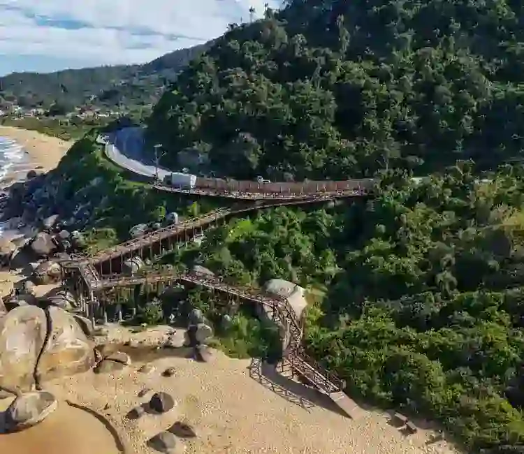 Deck de madeira na Praia de Taquarinhas, em Balneário Camboriú, cercado pela vegetação e próximo ao mar.